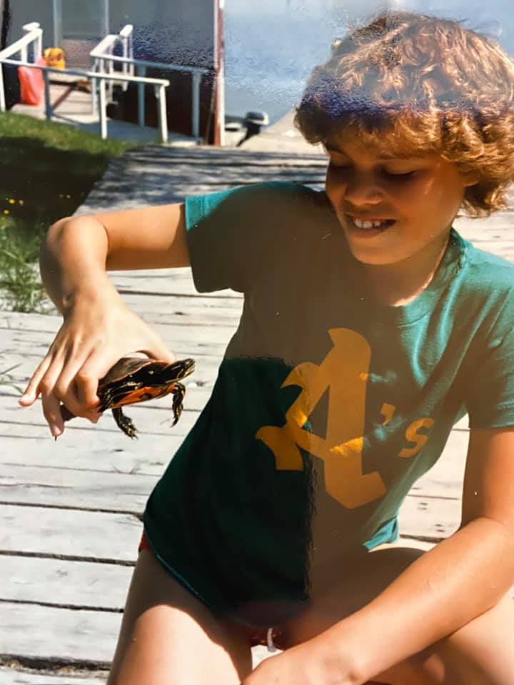 Girl with short hair holding a slider turtle.